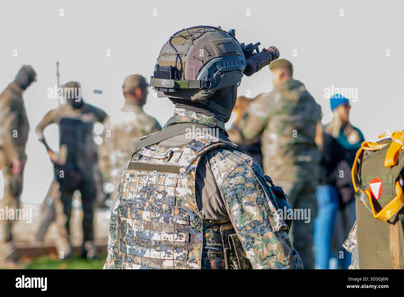 Un soldato che indossa un casco sta guardando le persone con uno scopo Foto Stock
