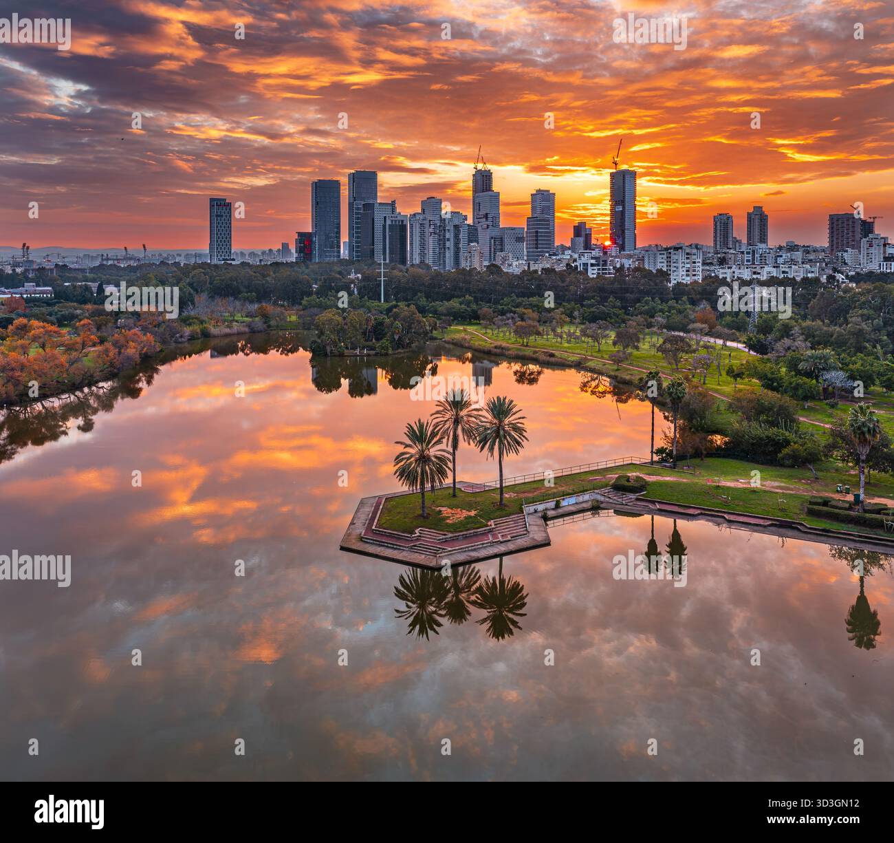Vista aerea del vibrante tramonto che si riflette sulle tranquille acque del Parco Hayarkon, in contrasto con il moderno skyline di Tel Aviv-Yafo, Tel Aviv Dis Foto Stock