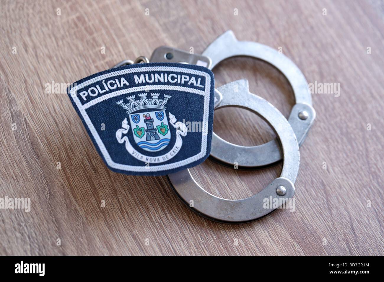 KIEV, UCRAINA - 6 SETTEMBRE 2025 Portogallo patch della polizia municipale e vecchie manette di metallo sul tavolo da vicino Foto Stock