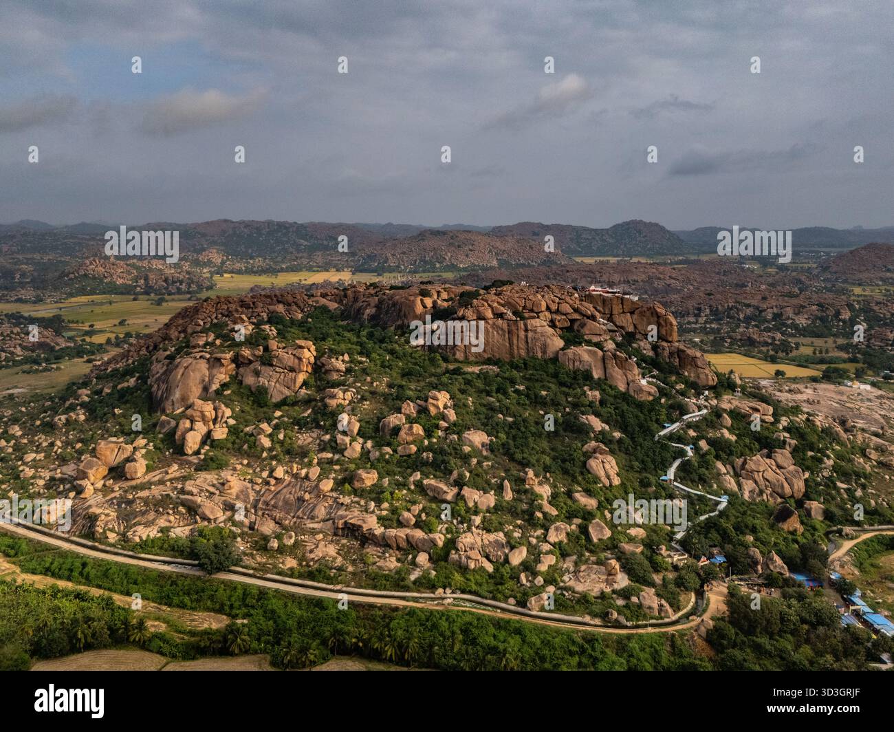 Vista aerea di terreni accidentati con massi sparsi e vegetazione sparsa sotto un vasto cielo, Hampi, Karnataka, India. Foto Stock