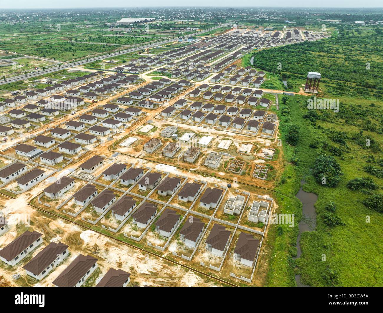 Vista aerea di file di case in costruzione, con i loro tetti marrone che contrastano con il verde circostante, Abuja, Nigeria. Foto Stock