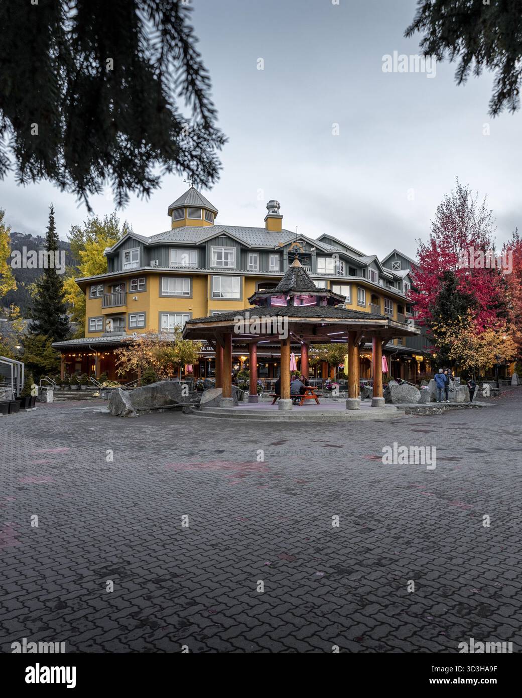Vista di un edificio giallo con tetto a cupola, incorniciato da colorati alberi autunnali, Whistler, British Columbia, Canada. Foto Stock