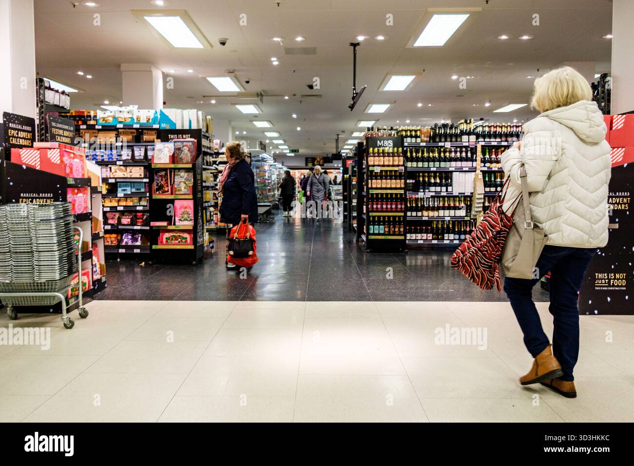 Londra Regno Unito, 06 novembre 2025, donna anziana che entra A Marks and Spencer Foodhall portando borse della spesa Foto Stock