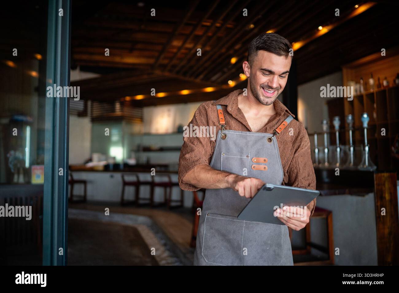 Barista appassionato e imprenditore che porta calore e servizio di qualità nella sua elegante caffetteria Foto Stock