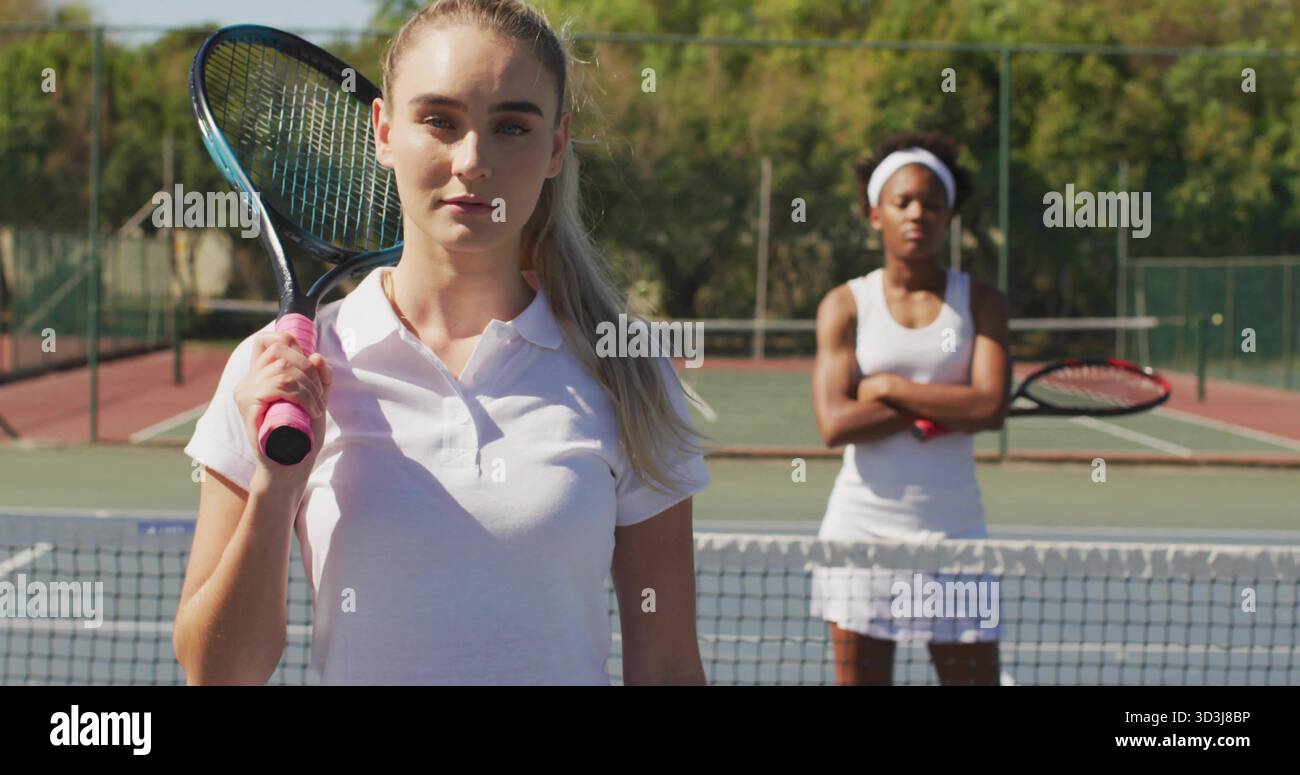 In piedi sul campo, tennista che indossa un vestito da tennis bianco con racchetta e avversario dietro la rete Foto Stock