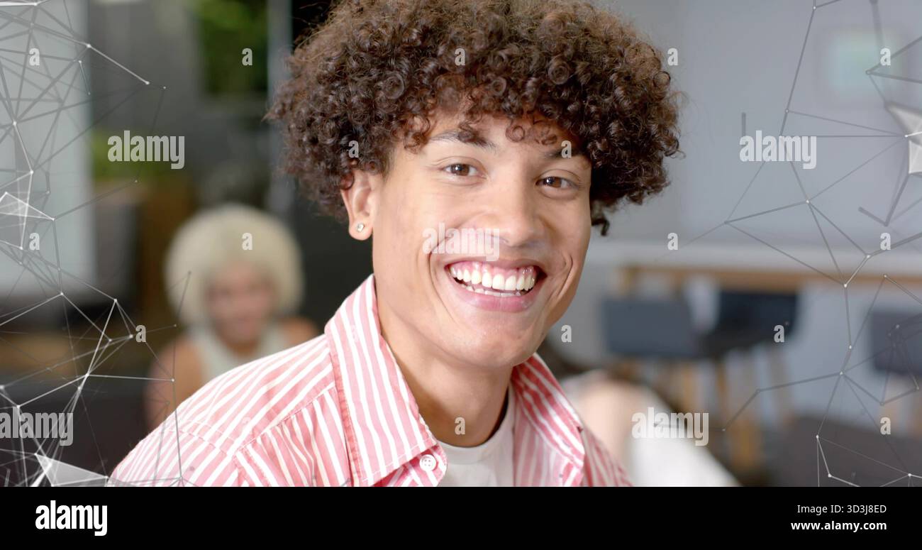 Uomo sorridente seduto in ufficio con una camicia a righe che mostra orecchini, sedie e mascherina di rete Foto Stock