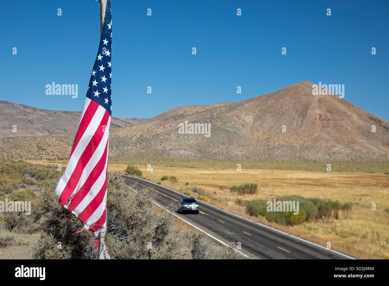 Austin, Nevada - Una bandiera vola nel deserto del Nevada sopra l'autostrada statale 305. La bandiera si trova sul sito di una ex Nevada Central Railroad. stazione. Foto Stock
