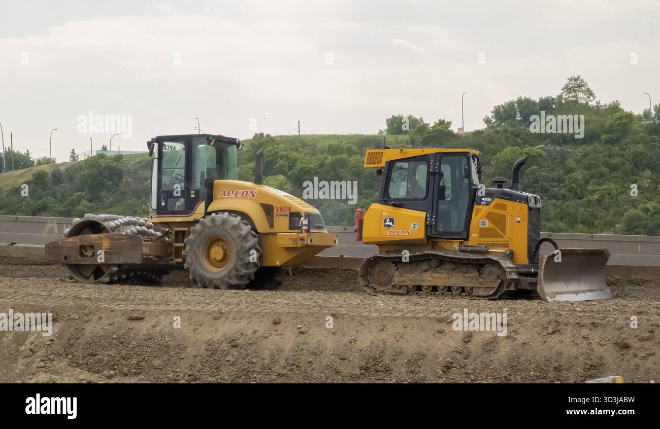 Calgary, Alberta, Canada. 8 giugno 2025. Due veicoli da costruzione gialli, un compattatore e un bulldozer, si trovano su una strada sterrata, a simboleggiare l'orecchio per impieghi gravosi Foto Stock