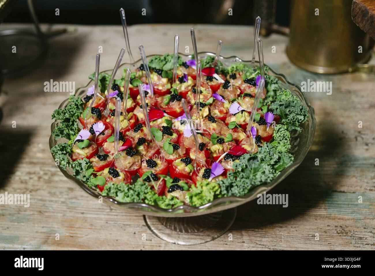 Cibo, Un piatto di antipasti ben organizzato con tartare di tonno in pomodori ciliegini, guarnito con caviale, microgreen e fiori commestibili Foto Stock
