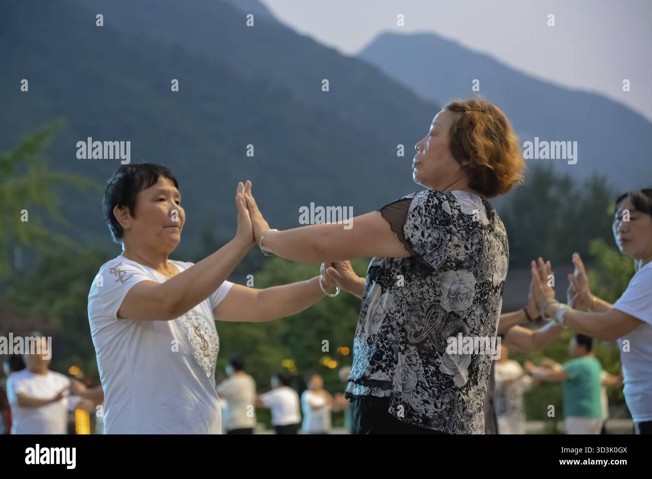 Huashan, Cina - agosto 2019 : gruppo di donne cinesi che ballano nella piazza aperta ai piedi del monte Huashan al crepuscolo, nella provincia di Shaanxi Foto Stock