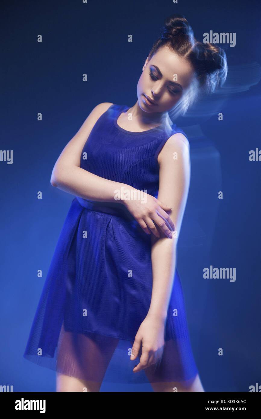 Ritratto di giovane e bella modello in posa vestito blu contro di sfondo blu.lunga esposizione Foto Stock