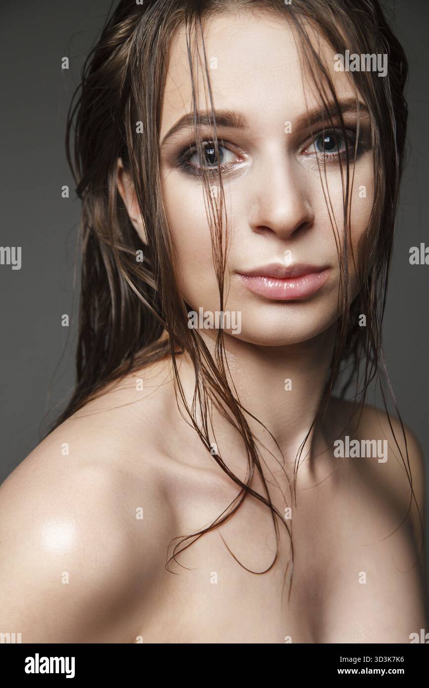 Bellissimo modello giovane con capelli bagnati e trucco che guarda la fotocamera Foto Stock