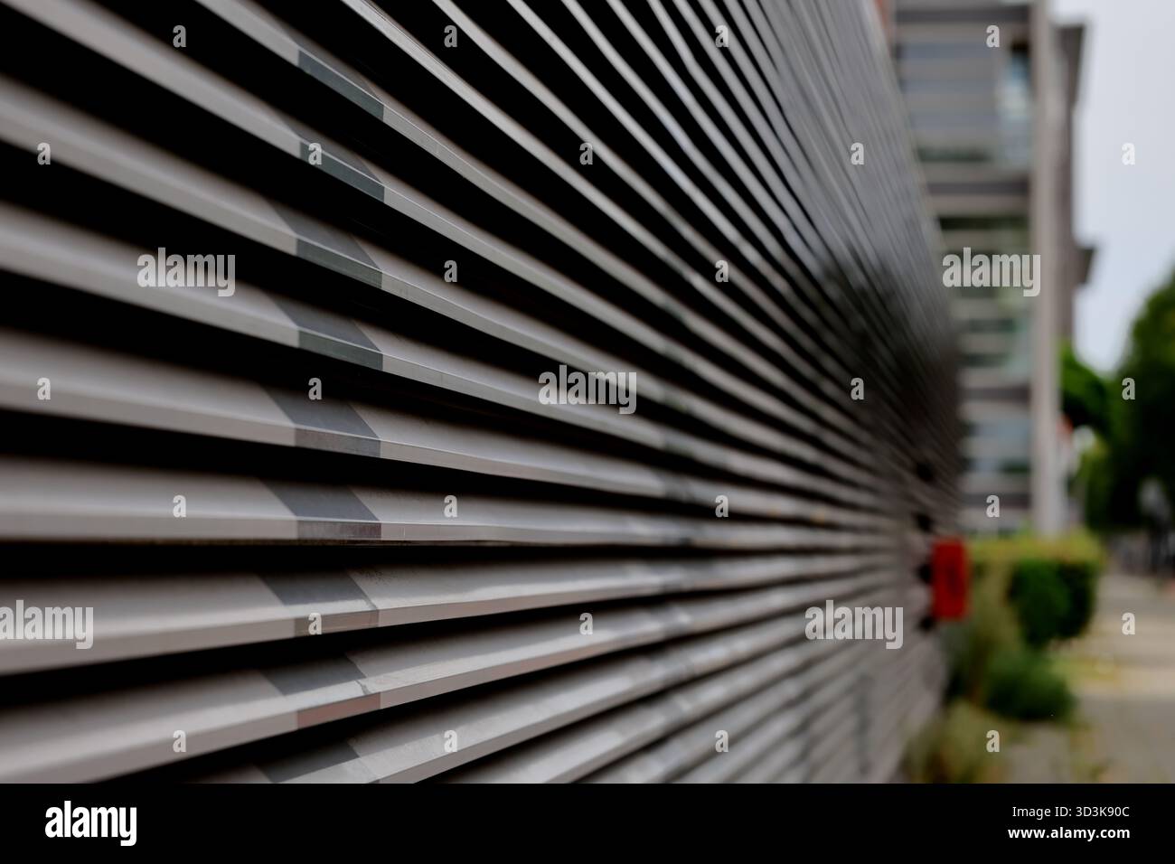 Prospettiva ravvicinata della facciata con feritoie metalliche su Zeeburgerdijk, Amsterdam, Paesi Bassi, con profondità di campo ridotta e linee di rientro lungo la strada. Foto Stock