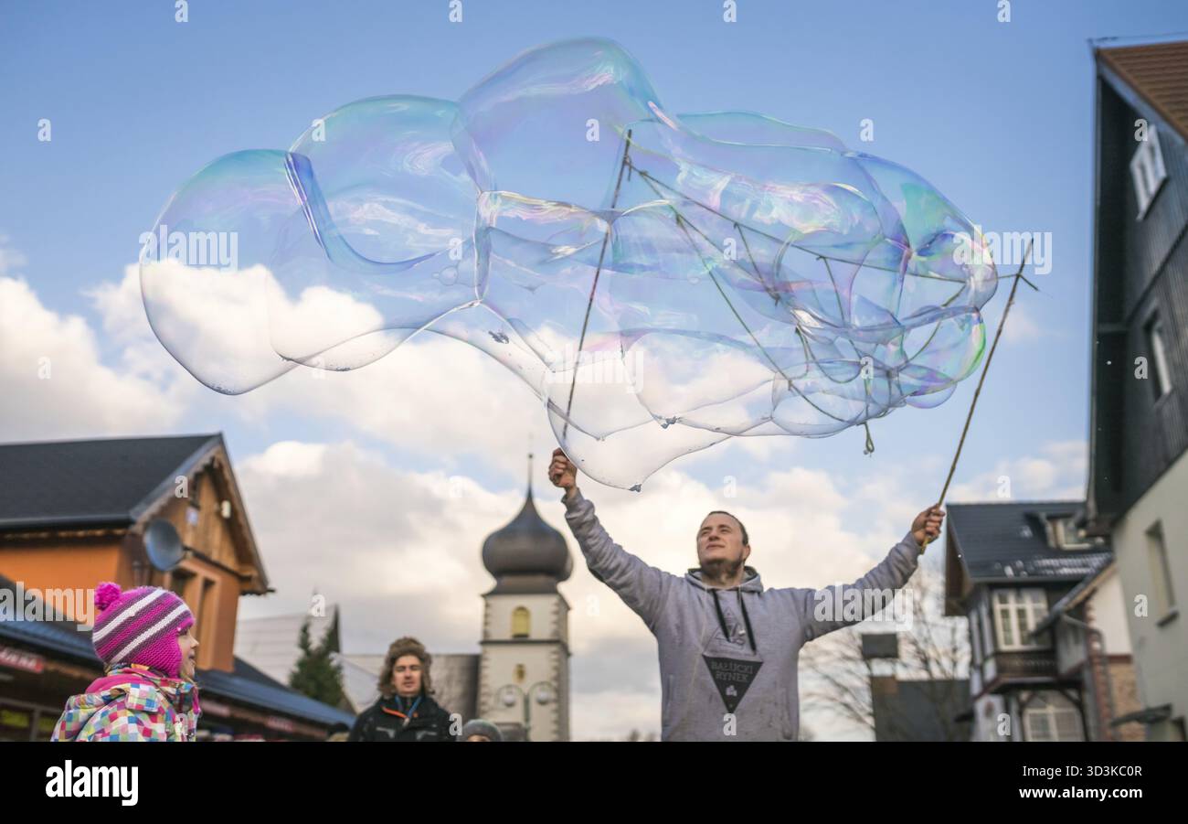Karpacz, Polonia - Febbraio 2018 : l'uomo gigante di rilascio di bolle di sapone per i bambini a prendere la strada principale che porta in città Karpacz, polacco sci invernale ri Foto Stock