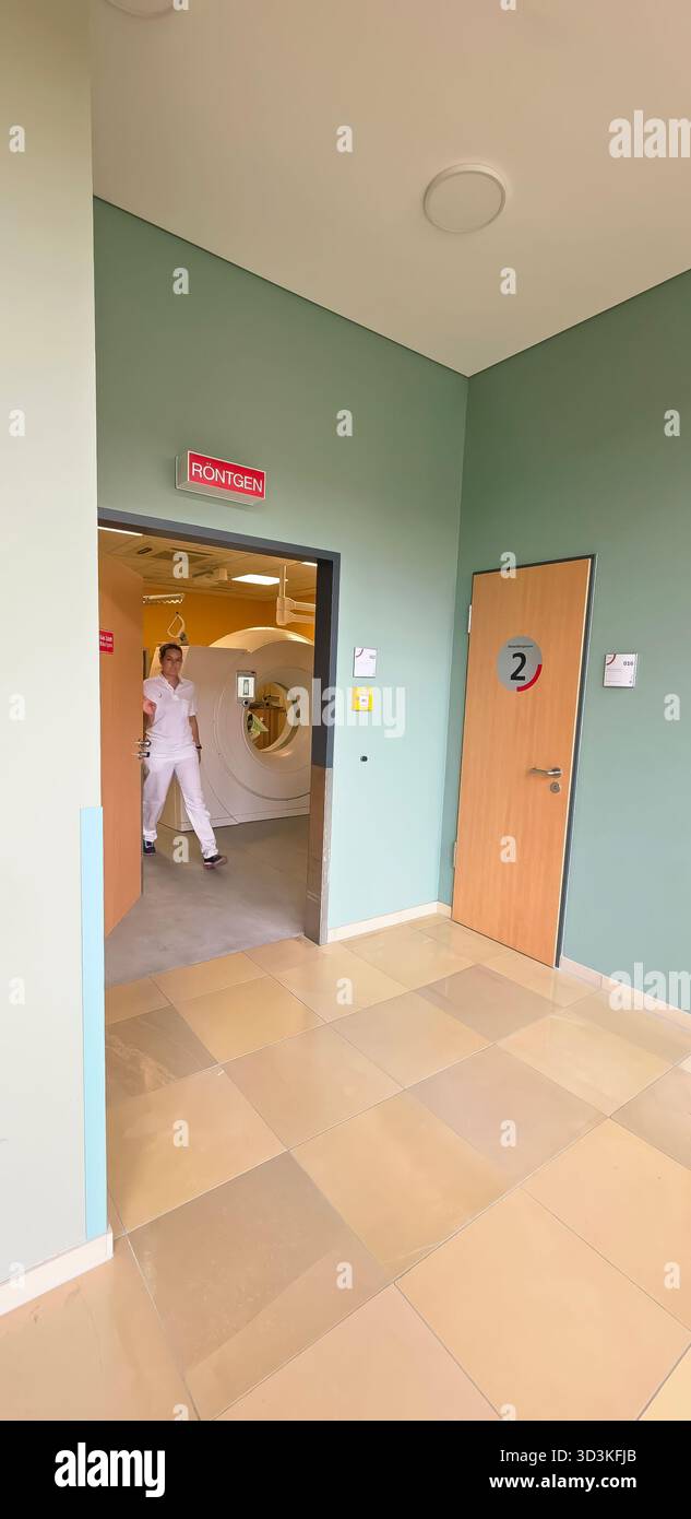 Berlino, Germania - 16 giugno 2025: Tecnico medico in uniforme bianca che cammina attraverso il corridoio dell'ospedale con spazio per le copie. - Immagine stock catturata con smartphone