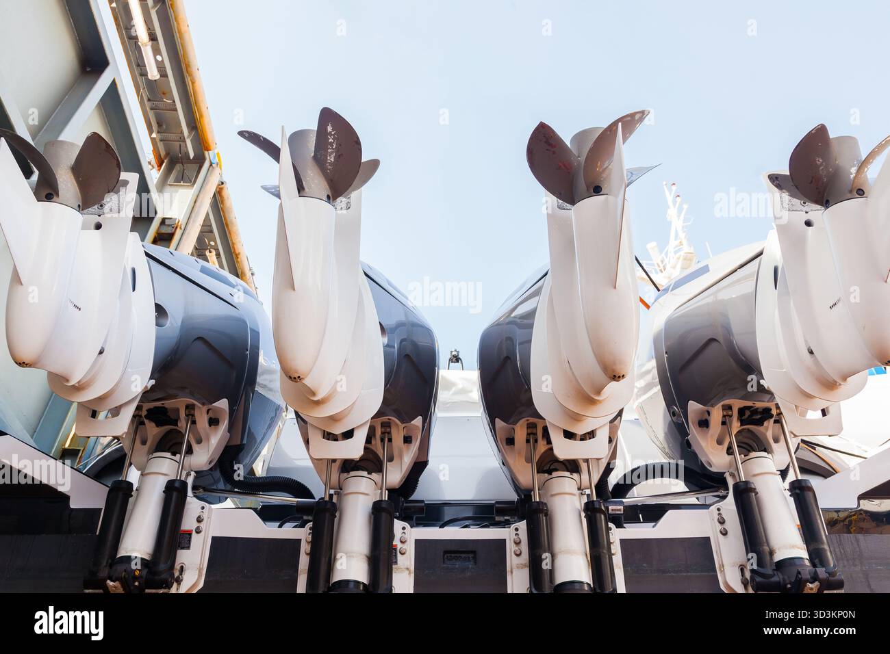 Quattro motori fuoribordo contro il cielo, montati su un'imbarcazione nel bacino di carenaggio, vista dal basso. Foto Stock