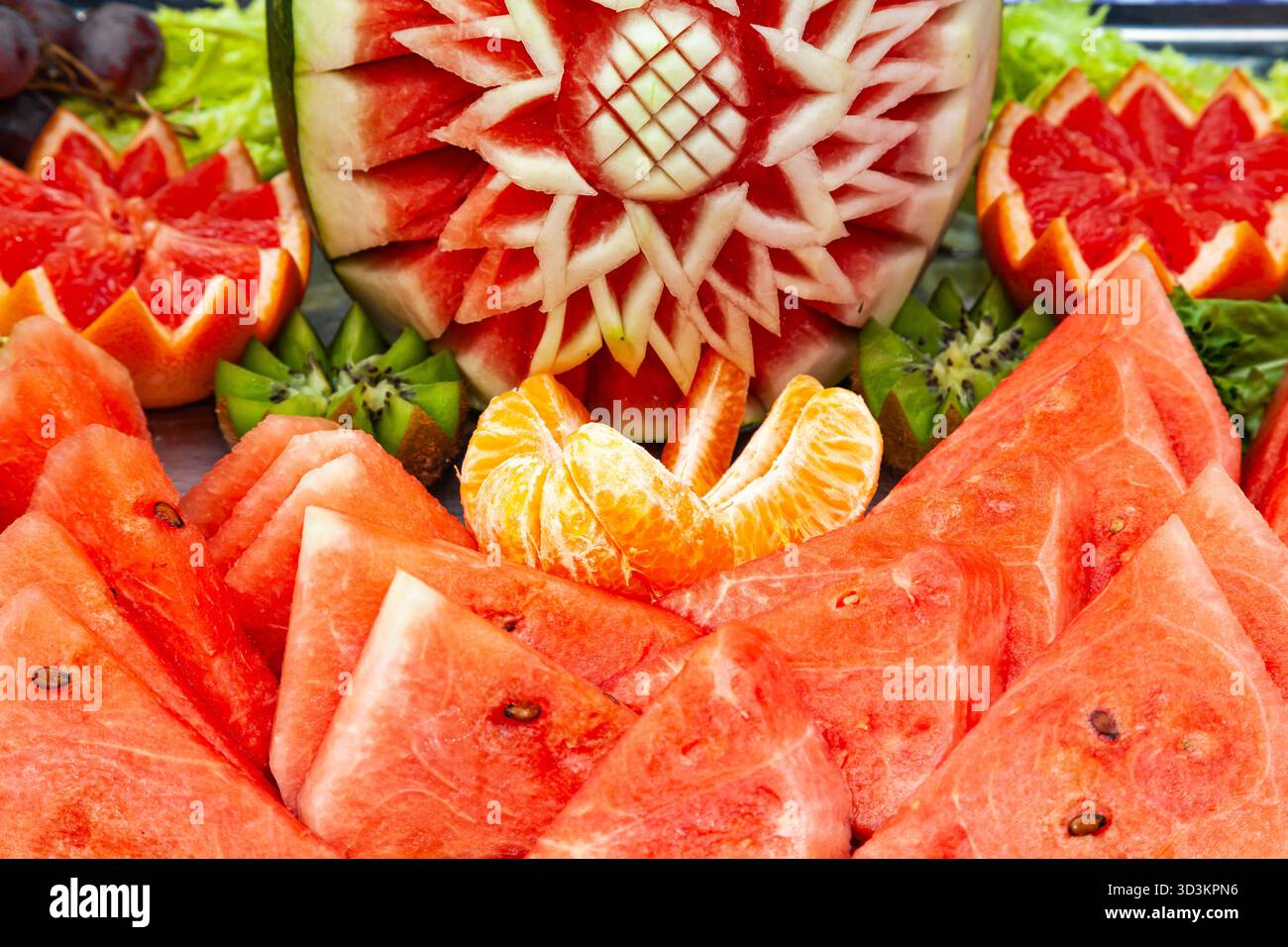 Frutta a fette decorativamente. Pezzi di anguria, kiwi, arancia e pompelmo Foto Stock
