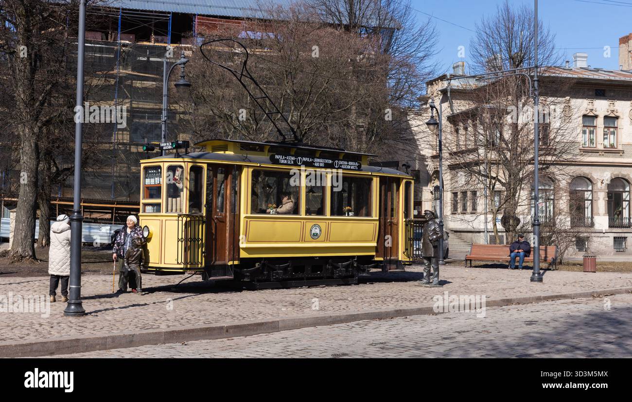 Vyborg, Russia - 16 aprile 2023: La caffetteria del tram giallo d'epoca si trova su una strada della città vecchia di Vyborg, la gente cammina per la strada in una giornata di sole Foto Stock