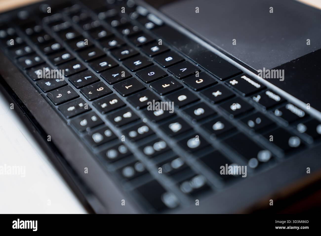 Vista ravvicinata della moderna tastiera nera per laptop con caratteri latini che mostrano un design compatto dei tasti a chiclet e un bordo liscio del touchpad per computer moderni Foto Stock