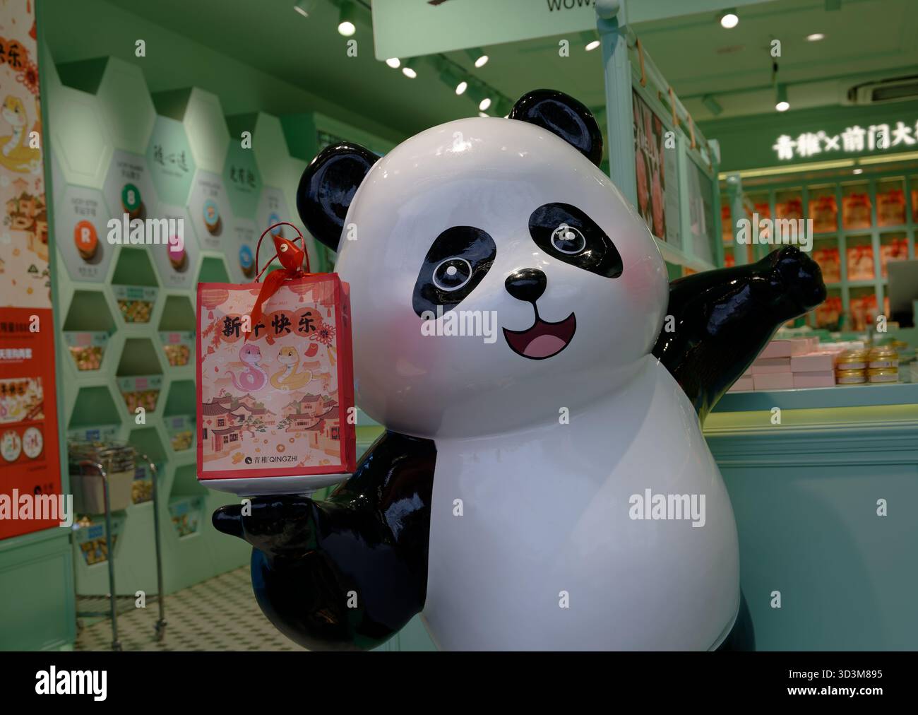 La mascotte Panda all'interno di un luminoso negozio di Pechino contiene una borsa regalo natalizia Foto Stock