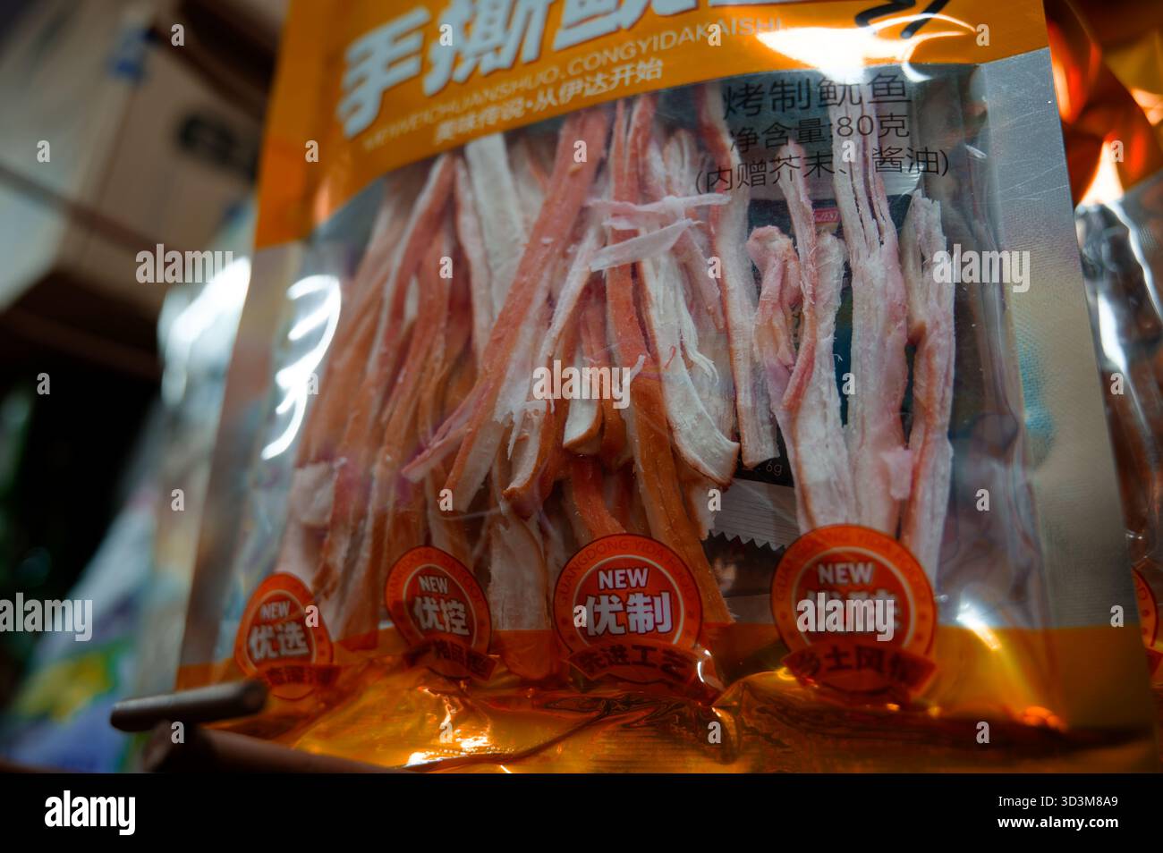 Strisce di calamari secchi imballate esposte sotto l'illuminazione del punto vendita Foto Stock