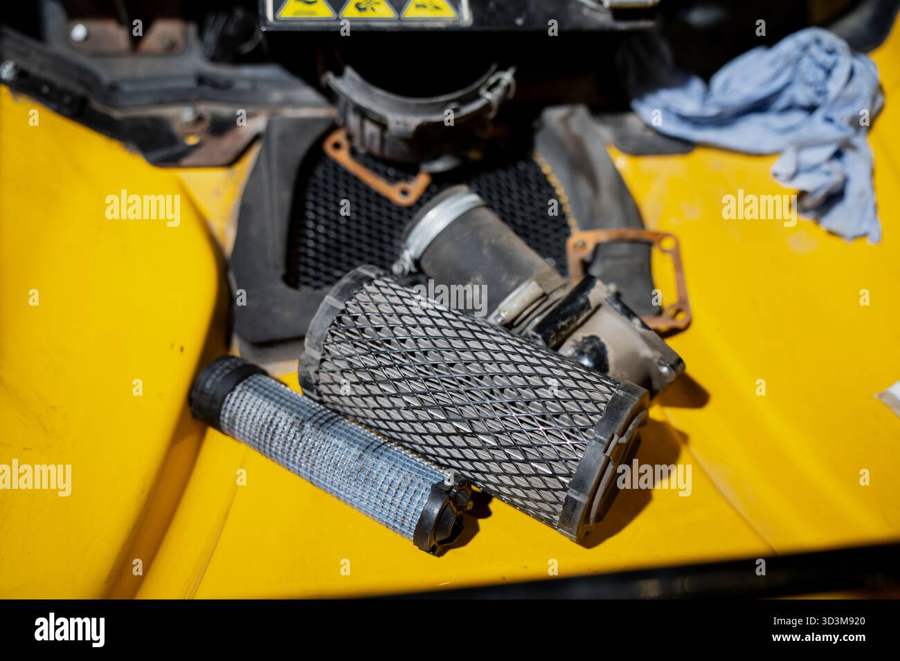 Filtri dell'aria per macchinari industriali e parti del motore su una superficie gialla che mostra polvere, utensili di manutenzione e dettagli costruttivi meccanici utilizzati per la repa Foto Stock