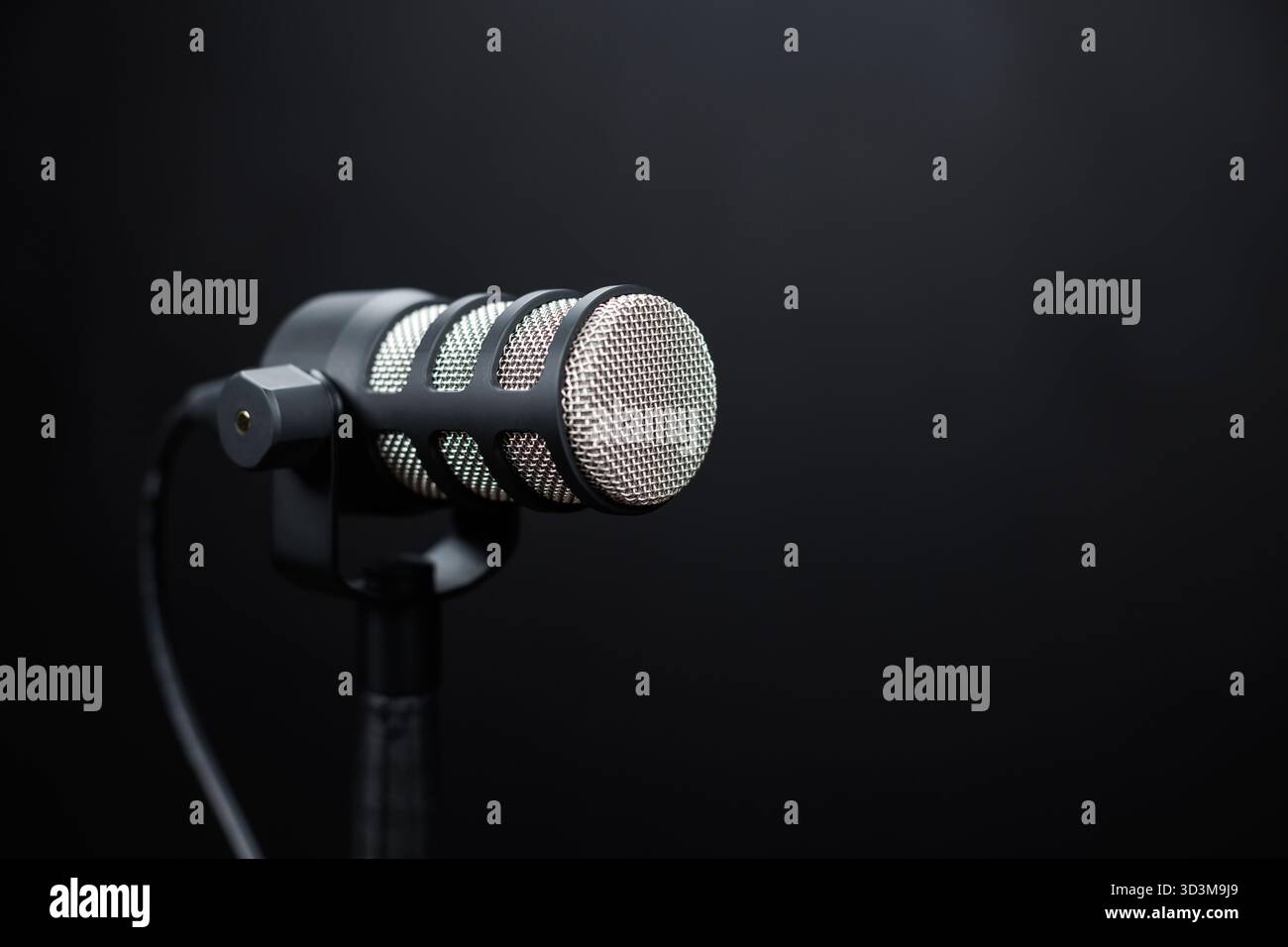 Microfono da studio su sfondo scuro. Microfono professionale per podcasting, trasmissione e registrazione vocale in configurazione studio con illuminazione soffusa. Foto Stock