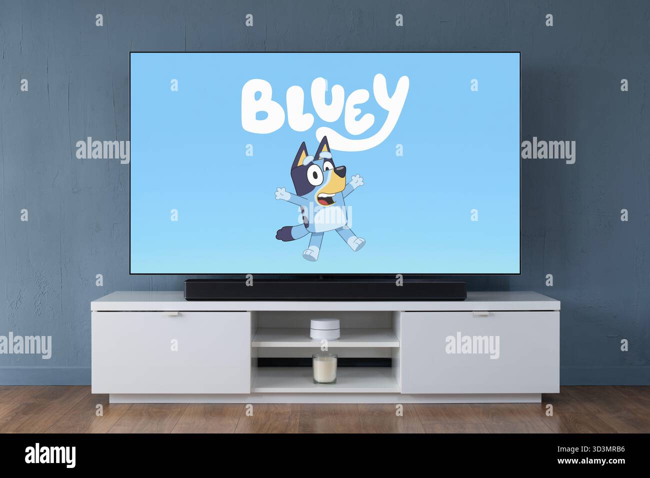 Un televisore OLED widescreen che mostra la scena introduttiva della serie TV per bambini Bluey, visto in un salotto contemporaneo. Foto Stock