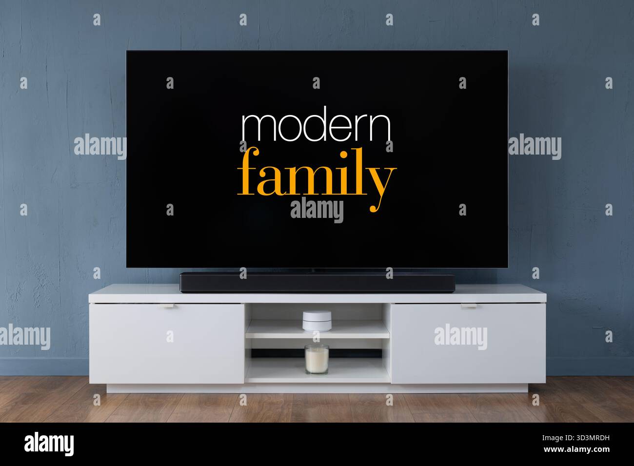Un televisore OLED widescreen che mostra la scena introduttiva della serie TV Modern Family, visto in un salotto contemporaneo. Foto Stock