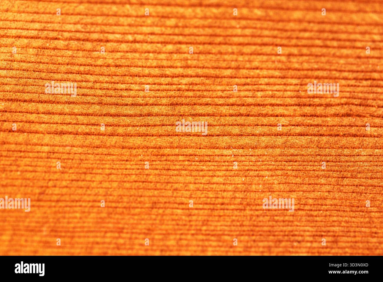 Creste arancioni testurizzate che evocano la venatura del legno con calde tonalità ambrate. L'illuminazione soffusa mette in risalto le linee parallele, creando profondità e fascino tattile. Astratto Foto Stock