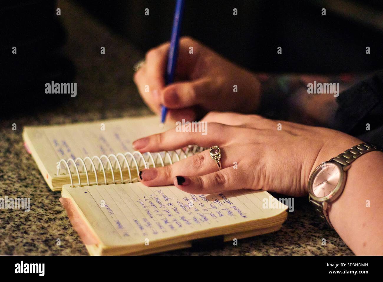 Le mani di una giovane donna, scrivendo e prendendo appunti nel suo taccuino, evidenziando dettagli, parole, sottolineature, colori, e il movimento della sua matita. Foto Stock