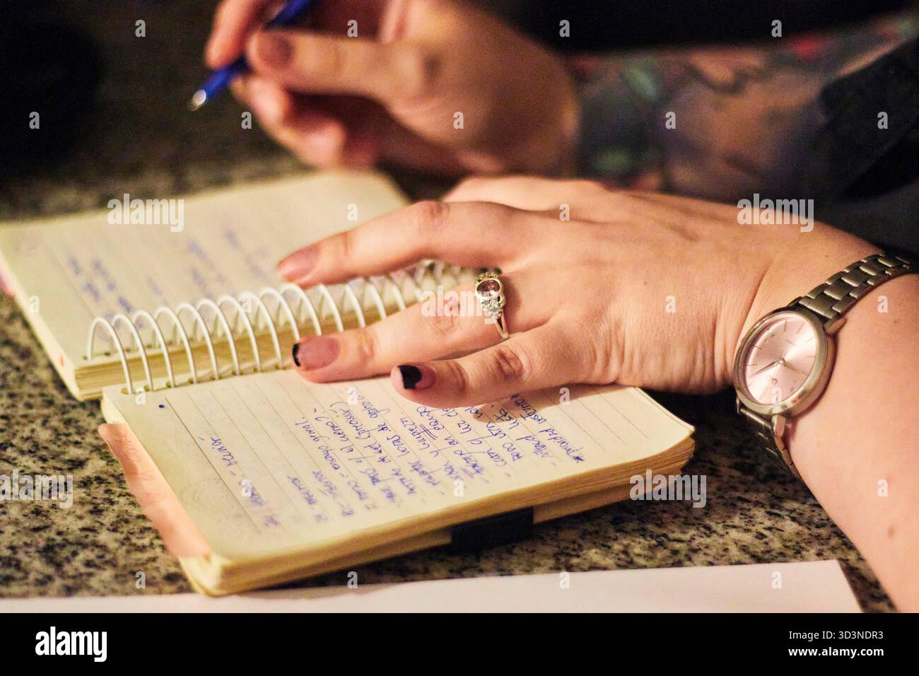Le mani di una giovane donna, scrivendo e prendendo appunti nel suo taccuino, evidenziando dettagli, parole, sottolineature, colori, e il movimento della sua matita. Foto Stock