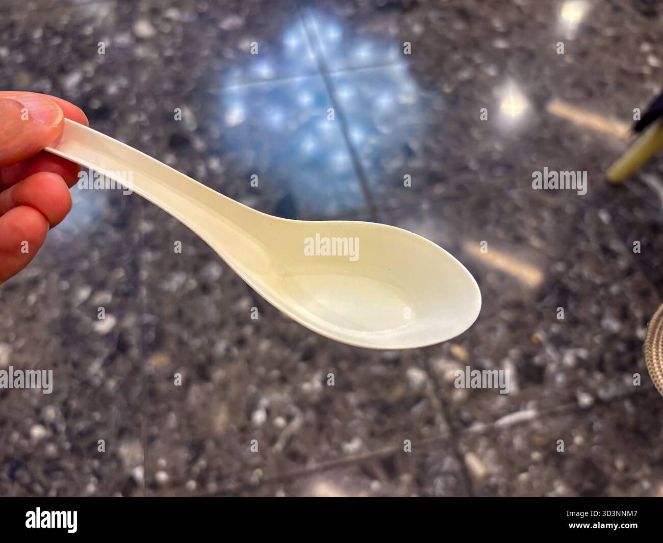 Cucchiaio ecologico tenuto da una mano. Questo utensile usa e getta è realizzato in materiale sostenibile e biodegradabile, che favorisce un li rispettoso dell'ambiente Foto Stock