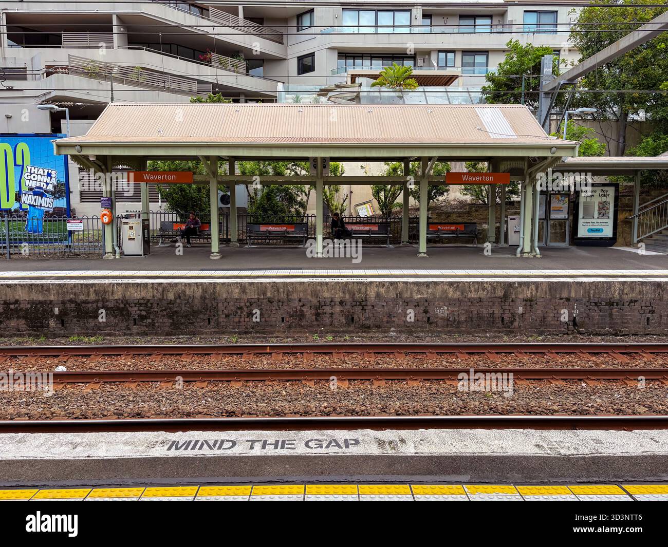 Stazione ferroviaria di Waverton, Sydney, Australia. Vista della piattaforma, dei binari e del rifugio con le persone in attesa. "Mind the Gap" visibile sul bordo della piattaforma. Foto Stock