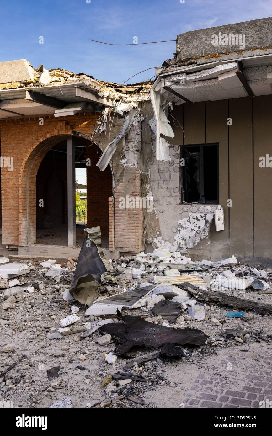 Vista aerea del tetto e della facciata in cemento in mattoni crollati strappati, isolamento e macerie sparse sul terreno, arco e telaio della finestra Foto Stock