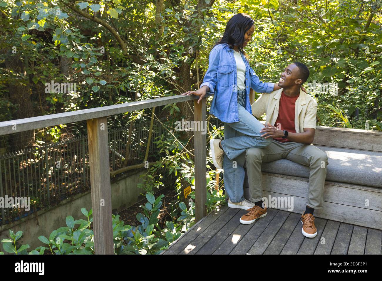 Coppia afroamericana pendente che condivide i momenti sul ponte di legno, con panca e ringhiera, spazio fotocopie Foto Stock