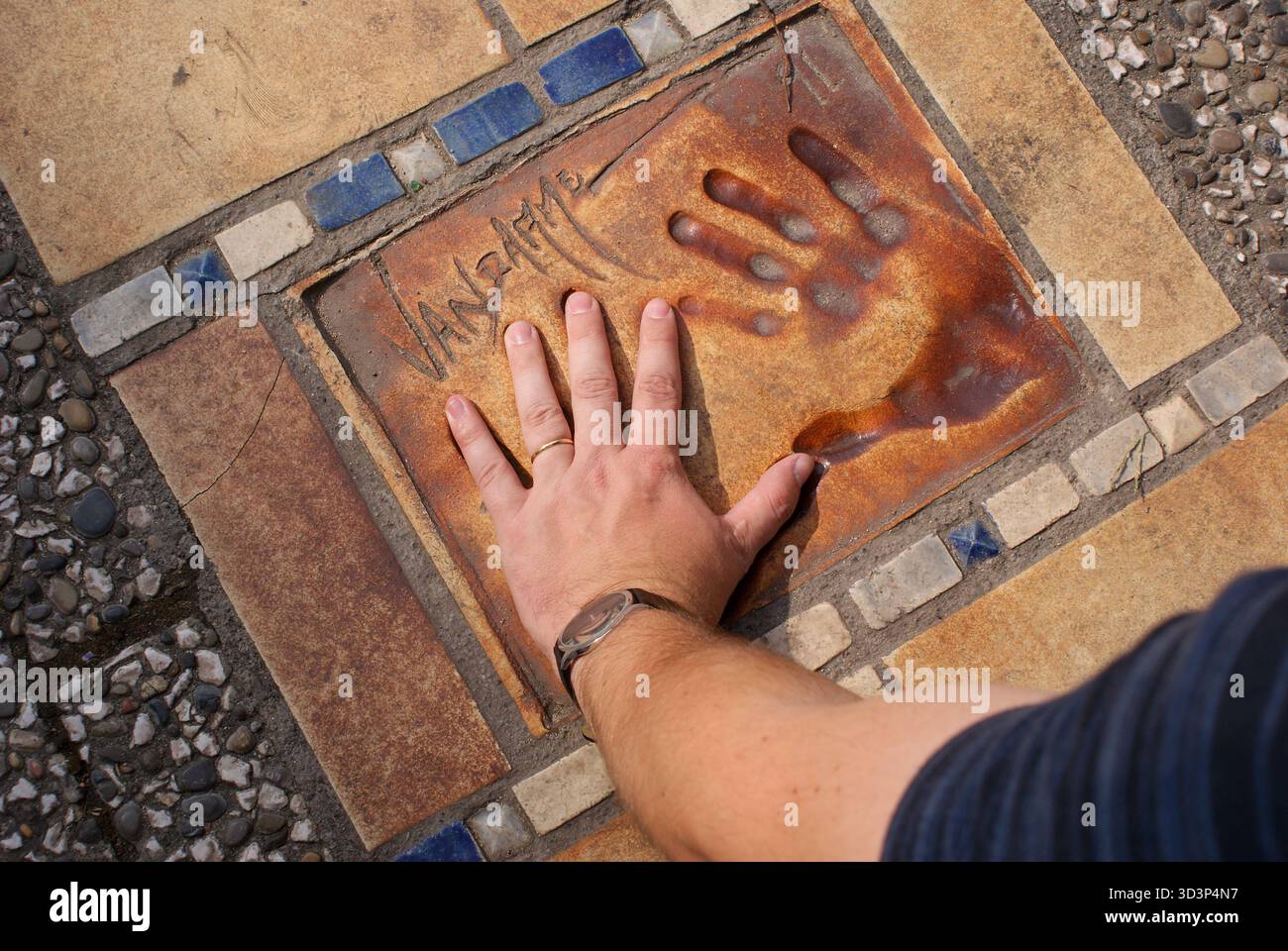 Mano della persona che entra in contatto con un'impronta commemorativa e firma di jean van hamme su una piastrella esterna Foto Stock