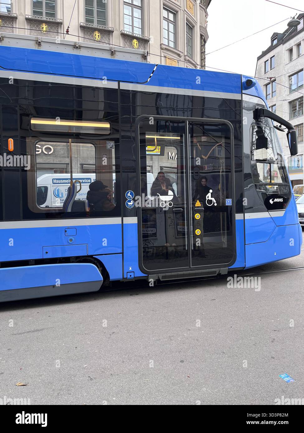 Un tram con simboli per disabili e passeggino alla porta guida su una strada di Monaco, in Germania Foto Stock