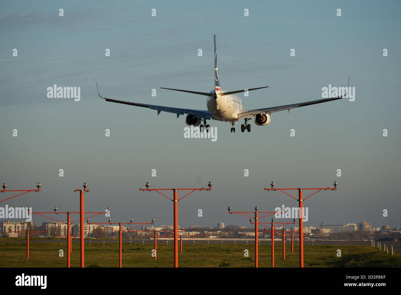 Un aereo di linea sorvola i poli di illuminazione di avvicinamento, secondi prima di atterrare sulla pista Foto Stock