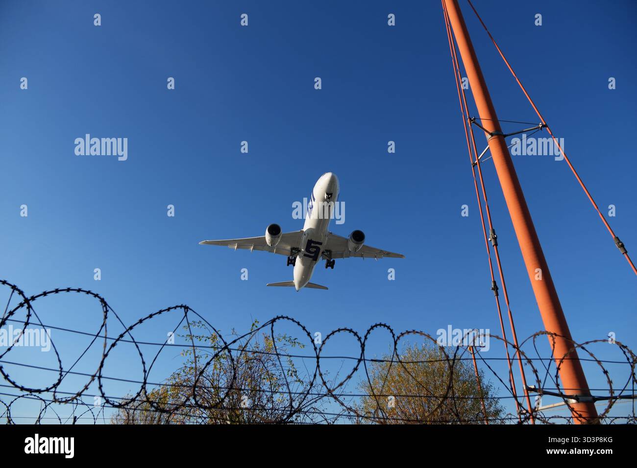 Un aereo di linea che scende per atterrare, sorvolando la recinzione perimetrale dell'aeroporto Foto Stock