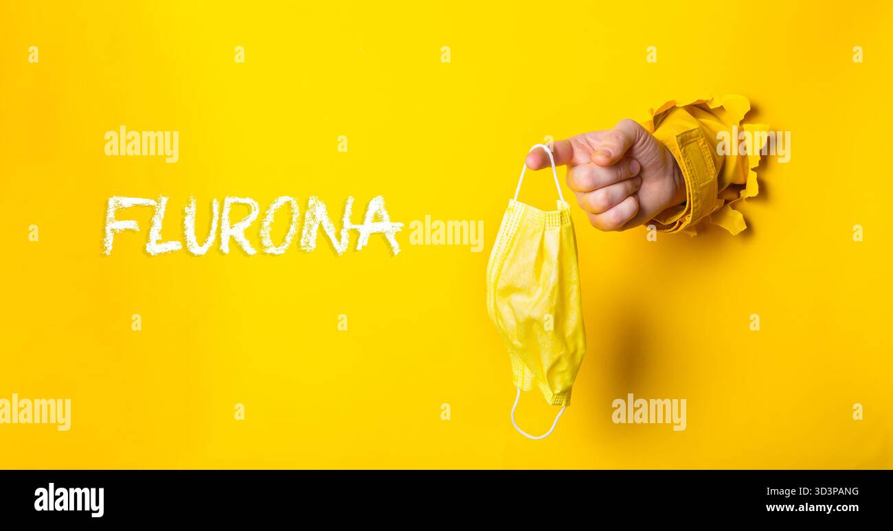 Persona che tiene una maschera gialla con la parola Fluorna scritta in bianco. L'immagine ha un umore giocoso e umoristico, poiché la persona tiene la maschera in una Foto Stock