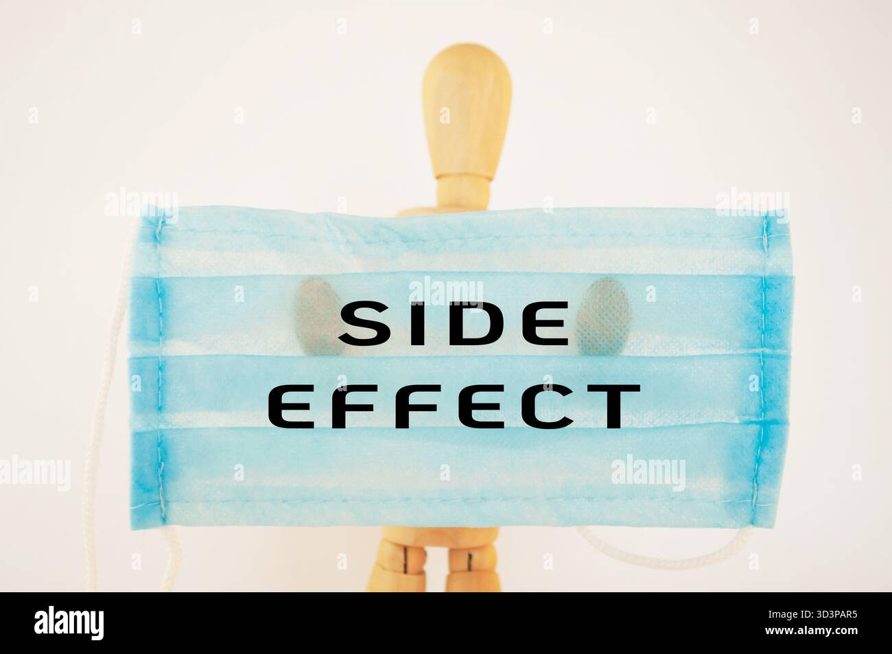 L'uomo ha una maschera chirurgica blu con le parole effetto collaterale scritte sopra. Concetto di attenzione e consapevolezza dei potenziali rischi associati al wi Foto Stock