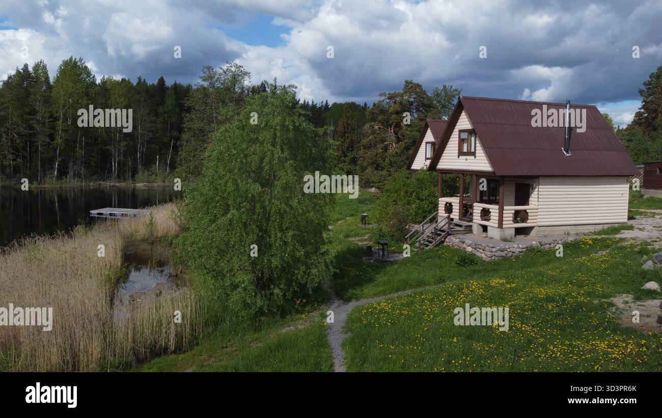 Cottage in legno vicino al lago forestale: Tranquillo rifugio di campagna nella natura estiva Foto Stock