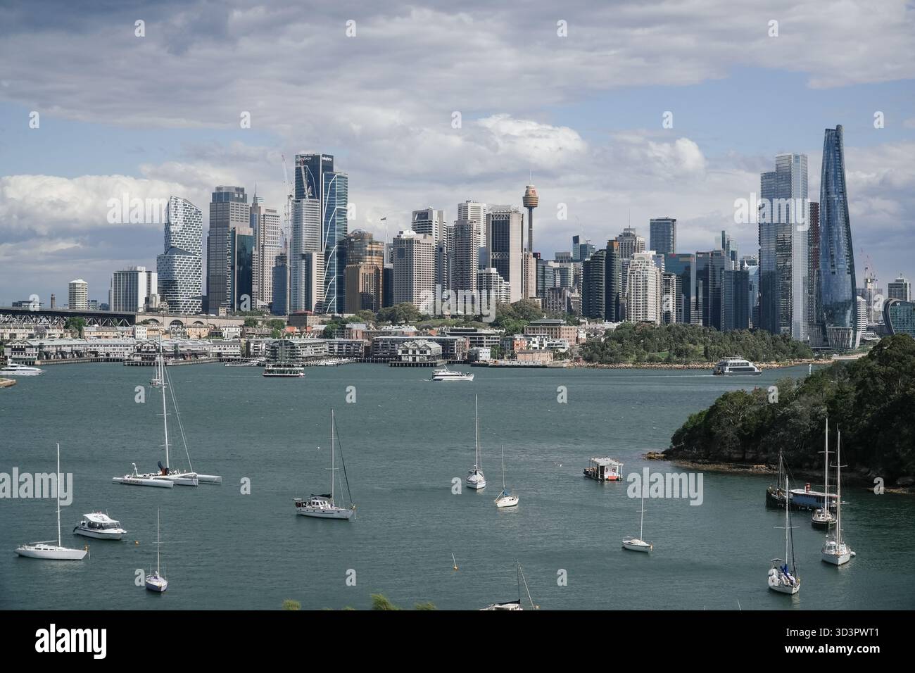 Lo skyline di Sydney presenta moderni grattacieli e l'iconica Sydney Tower Eye, vista attraverso una baia con numerose barche a vela e traghetti. Foto Stock