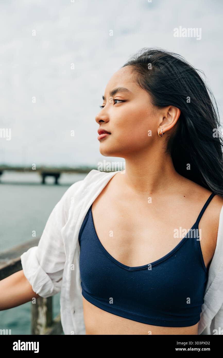 Giovane donna asiatica che contempla la vista sull'oceano dal molo Foto Stock