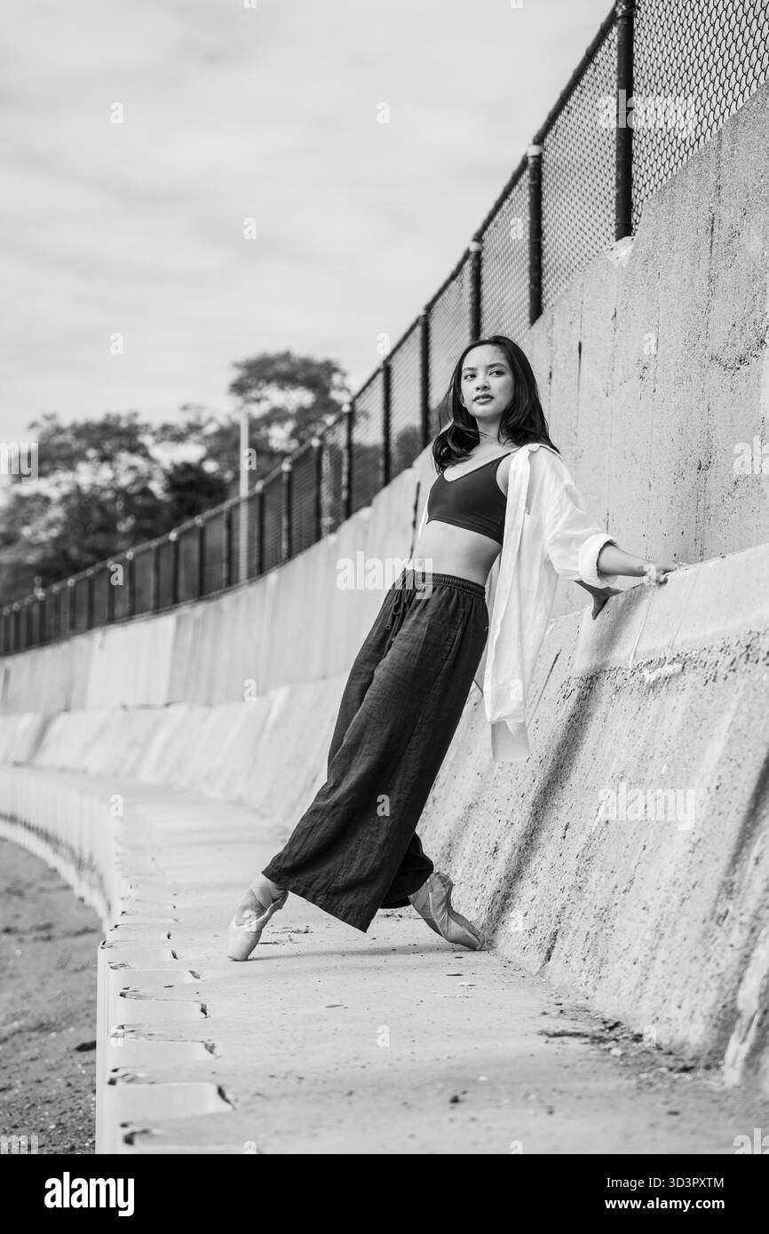 Ballerina su pointe in equilibrio con il muro di cemento urbano Foto Stock