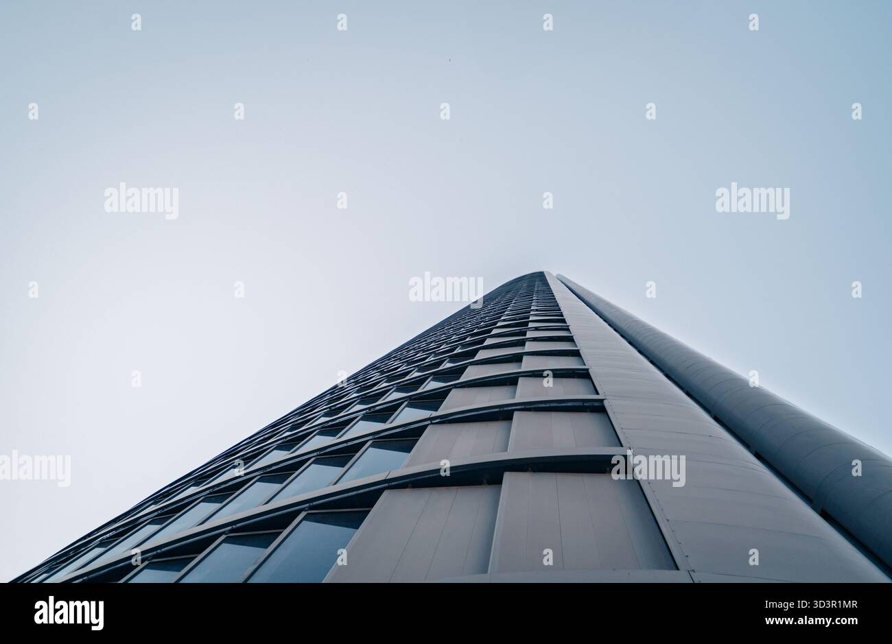 Una suggestiva vista ad angolo basso di un moderno grattacielo, parte dell'area finanziaria di Cinco Torres a Madrid, Spagna. Le linee sottili e il vetro riflettono la nitidezza Foto Stock