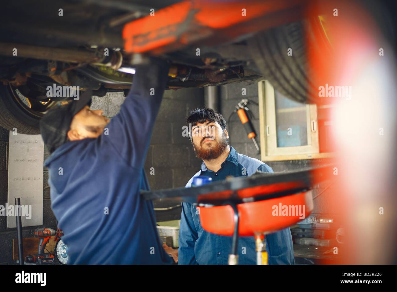 Due meccanici si concentrano sulla riparazione di un veicolo in un garage Foto Stock