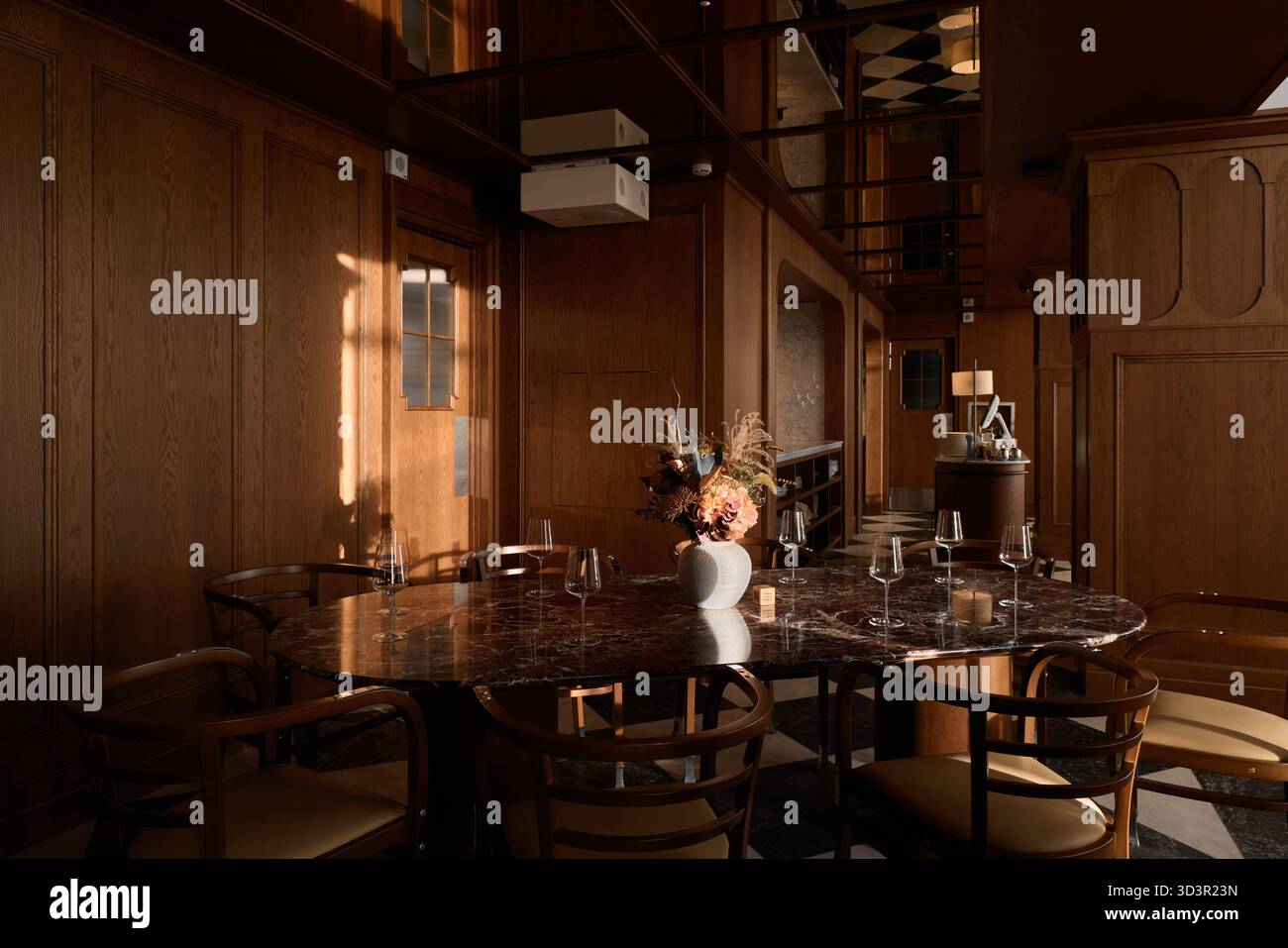 La calda luce della sera riempie un'elegante zona pranzo in uno spazio moderno Foto Stock