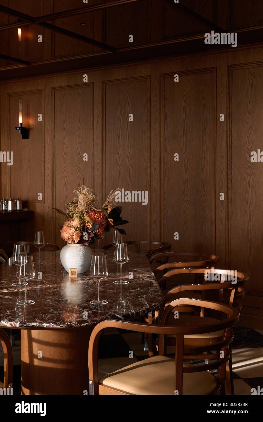 Elegante zona pranzo con centro floreale in tonalità calde Foto Stock